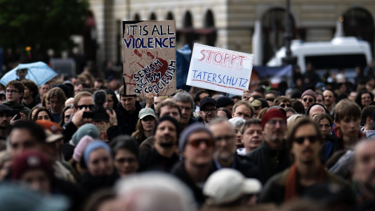 Menschenmenge und Demo-Plakat mit der Aufschrift "Stoppt Täterschutz" und weiteren