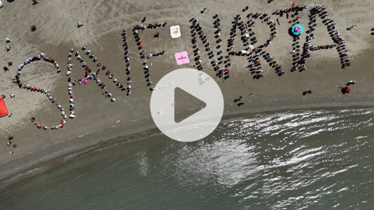 Foto: Aus der Luft sind Menschen am Strand zu sehen, die das Wort „SAVE NARTA“ bilden. Im Vordergrund liegt das Meer.